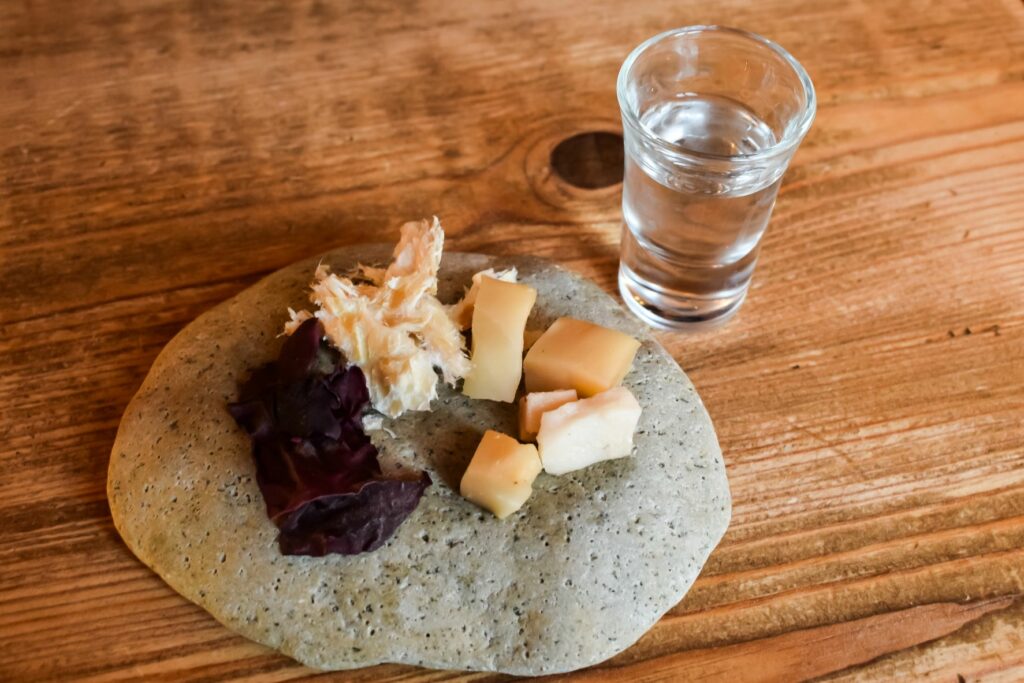 Diverses Haifleisch auf einem Steinteller mit Wodka an der Seite